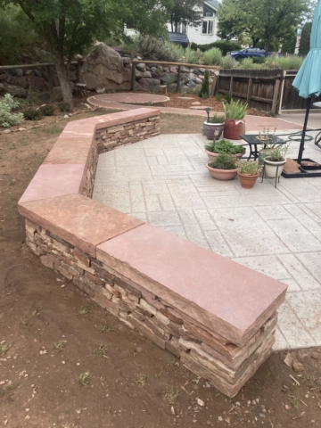 freestanding traditional dry stone wall with mortared sandstone slab cap, spiral flagstone patio visible
