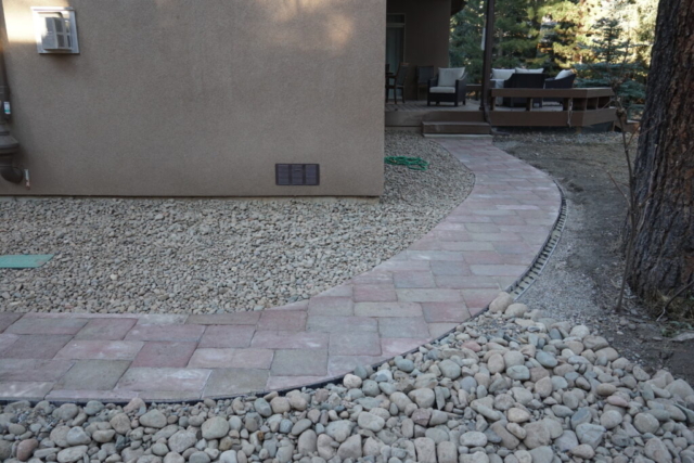 Paver pathway connecting driveway to back deck, dry creek bed french drain, with cobble landscaping along house