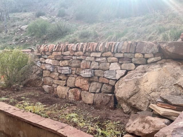 Major wall repair. Sandstone boulders hammerdrilled into workable pieces. Traditional double face dry stone wall with through stones and vertical copes. Stone Retaining wall rebuild.