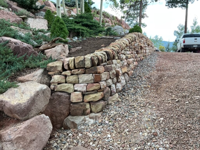 Sandstone traditional double face dry laid stone retaining wall with vertical copes and completed landscaping