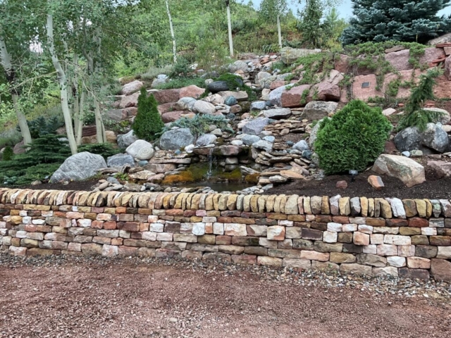 Sandstone traditional double face dry laid stone retaining wall with vertical copes with pond and water feature