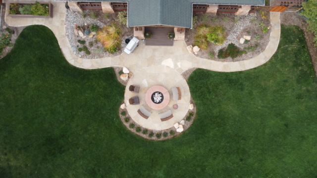 Bordered flagstone walkways and pations with large gas fire pit and grill. Herb garden and landscaping visible