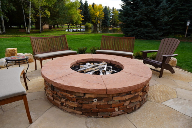 Dry laid stone fire pit with custom mortared sandstone cap and integrated utilities, centered on large flagstone patio