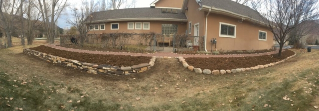 Traditional dry stone retaining wall used to terrace hillside, boulder landscaping and rustic stone pathway