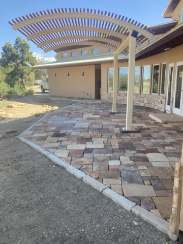 Dry laid natural stone paver patio with stone borders, stone stair, and natural stone slab landing under doors