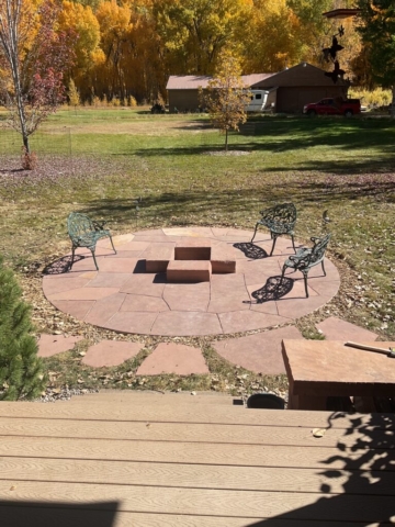 Circular flagstone patio with custom sandstone firepit, flagstone stepping path and sandstone slab woodshed visible