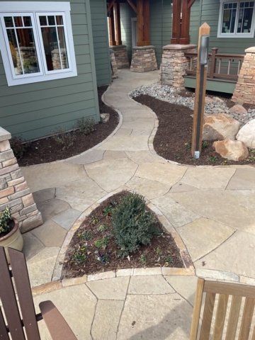 Flagstone patio and flagstone walkway artistically shaped with stone borders and stone veneer columns