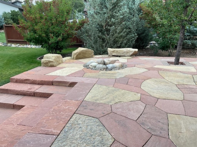 two tone flagstone patio, with custom sandstone slab staircase. boulder seating with rustic firepit featured.