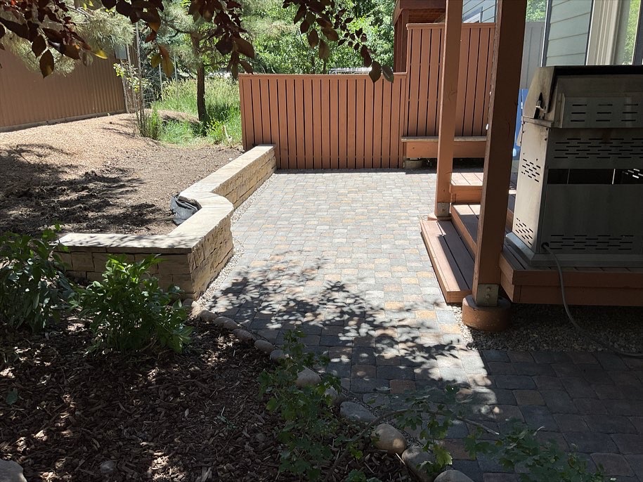 Paver patio with dry laid stone retaining wall with mortared cap