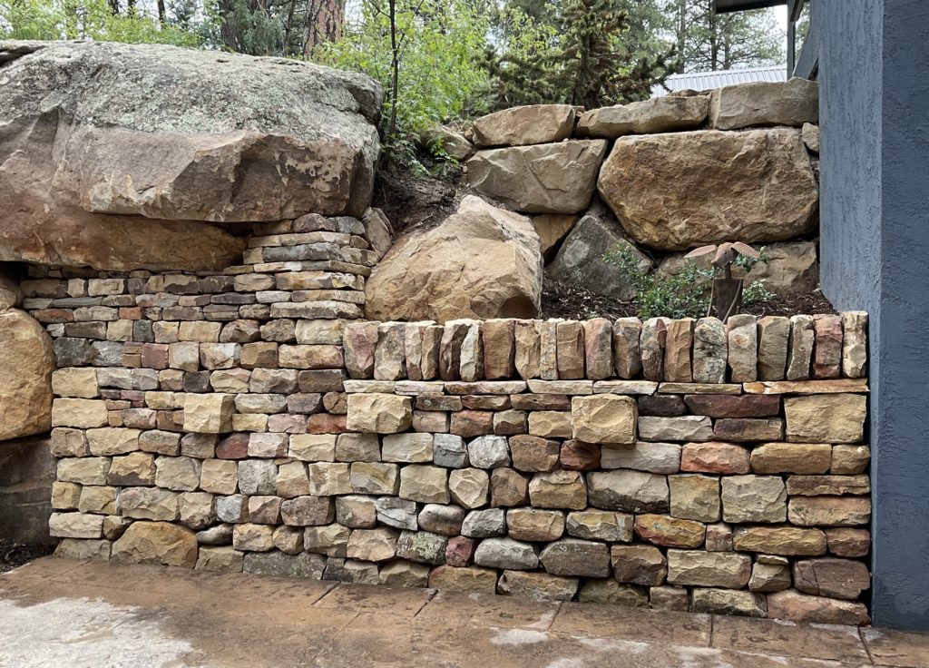Dry stone double stack retaining wall featuring sandstone, vertical coping stones, copes, and through stones