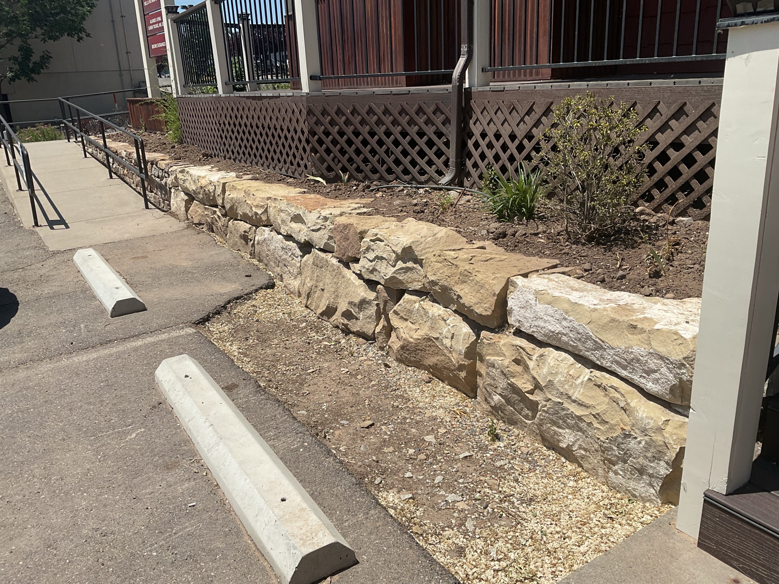 Boulder retaining wall for raised bed planters with a small traditional hand stacked dry stone wall visible