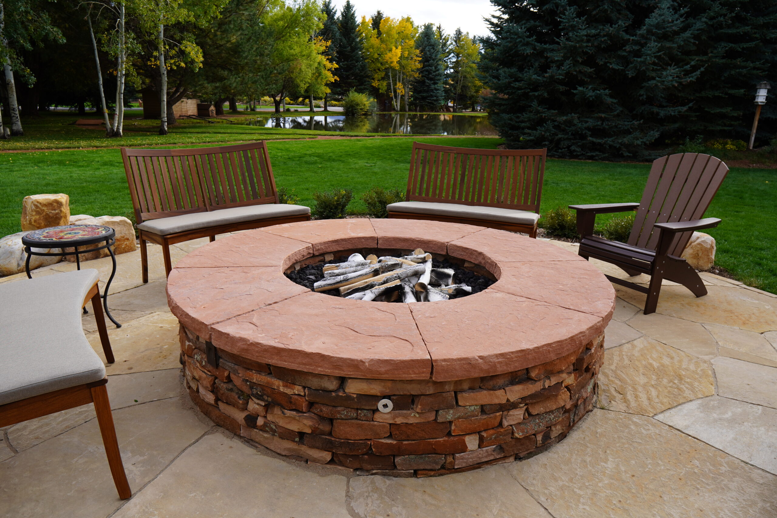 Dry laid stone fire pit with custom natural stone slab cap and integrated gas and electric utilities.