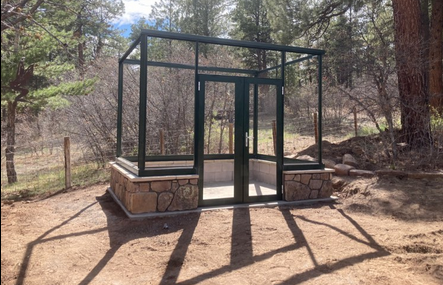 Greenhouse frame with concrete foundation, integrated water and electric utilities, block walls, and stone veneer